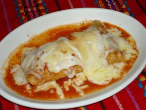 Deliciosa enchilada de maíz rellena de cerdo, queso Oaxaca y bañada en salsa roja picante. ¡Una explosión de sabores en cada bocado!