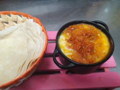 Delicioso queso fundido con cochinita pibil, servido con tortillas de harina para armar tacos irresistibles. ¡No te lo puedes perder!